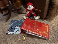 Wide view showing the Disney patch collection binder closed, Bugs Bunny plush and T-shirt folded beside it, Avengers watch in front