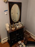 Full view of the Ethan Allen cabinet with various items on top and mirror mounted above