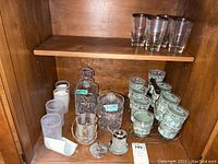 Galway decanter, lidded jar, frosted Portuguese poinsettia cups, jasperware style glasses in metal caddy, clear tumblers on wooden shelf