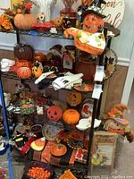 Full view of multiple shelves filled with various Halloween and fall decorations including pumpkins, candle holders, scarecrows, and decorative plates.