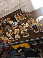 Multiple Hummel porcelain figurines displayed on a table, colors and details visible, various sizes from 4 to 8 inches tall.