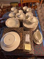 Full view of stacked Johann Haviland dinnerware set on table including plates, bowls, cups, sugary bowls, creamers, and boxed unopened items.