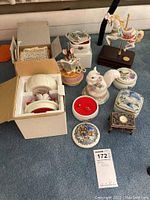 Full lot photo showing 10 ceramic and porcelain music boxes of varied designs including animal figurines and holiday themes.