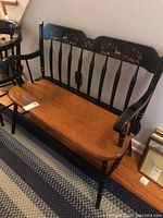 Full view of the wood bench showing natural wood seat, black painted legs and back, and stencil design on backrest.