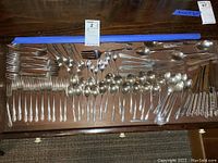 Wooden drawer with entire flatware set laid out, overview of all pieces