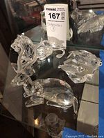 Front view of all four figurines on glass shelf showing gazelle, lion, and two seals.