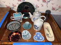 Wide view of lot showing Pfaltzgraff tea pot and jug, metal Pfaltzgraff tray, clear drinking glass, Wedgwood jasperware dishes, hand-painted floral tray, and various decorative ceramic bowls and dishes
