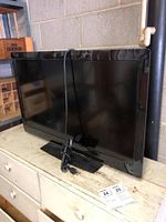 Full view of the Vizio E321MV 32-inch TV showing the screen, base stand, and attached power cord.
