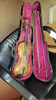 Full view of Roth violin inside black case with pink velvet lining, also showing one bow and chinrest details