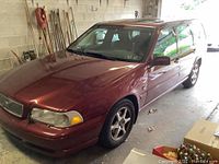 Front left quarter view of maroon Volvo V70 in garage