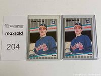 Two 1988 Fleer John Smoltz rookie baseball cards displayed side by side in protective sleeves with a MaxSold card for scale.