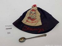 Photo showing Howdy Doody bucket hat front with embroidered 'Tommy' and metallic spoon alongside