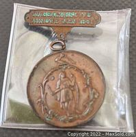 Photo of front face with bar and detailed dual-figure design of Massachusetts Minutemen 1861 medal in plastic sleeve.