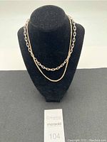 Full view of the two necklaces displayed on a black velvet bust stand, showing the chain link and rope styles.
