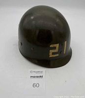 Photo showing front and one side of the WWII helmet liner with painted number "21" on outer surface.