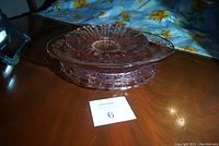 Side view of stacked oval dish and platters on wooden table showing pink glass.