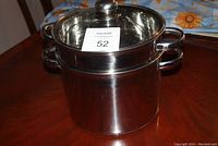 Full assembled pasta pot with steamer insert and glass lid on a wooden table.