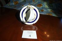 Photo shows Aynsley teacup nested inside the matching saucer with a stand holding them upright, displaying the cobalt blue and gold rim design.