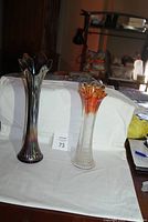 Photo showing both carnival glass vases on white backdrop with lot number tag.