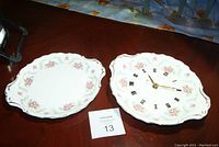 Top view of Royal Albert plates showing floral pattern and clock face on one plate with roman numerals and gold trim.