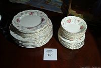Stacks of dinner, salad, and bread plates with floral rose and silver trim pattern.