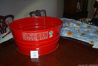 Red metal tub with Sleeman logo on the side, displayed on a table.