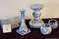 Group photo showing two blue and white ceramic candlesticks, ceramic box with Asian design, and four decorative ceramic balls in varied blue floral patterns.