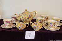 Full set displayed: six-cup teapot, creamer, sugar bowl with lid, four matching cups and saucers, and two additional Royal Cuthbertson cups and saucers