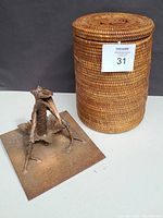 Photo of handmade Mexican woven frog basket with carved lid alongside the metal lizard king fountain base.