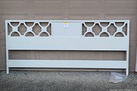 Front view of the king size headboard primed in white with geometric cutout design and mounting hardware included.