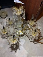 Overall top-down view showing the chandelier's six arms, brass-colored metal elements, plastic crystals, and bulbs.