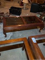 Photo of wood coffee table showing full top surface with two glass inset panels and curved carved legs. The table top shows scratches and some white residue.