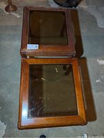 Top view of pair of wood end tables showing beveled glass inserts and wood frames