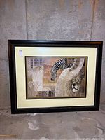 Front view of large framed and matted print showing African animals composition including lion, zebra, cheetah, elephant with earth tone background and black wood frame