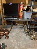 Square patio table with metal frame and glass top shown with items on top (not included). Scratches visible on metal frame. Hole in center of table for umbrella.