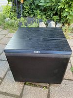 Front top angle showing black wood grain finish, grille with AE logo