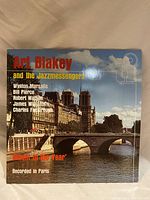 Front cover of Art Blakey and the Jazzmessengers 'Album of the Year' vinyl record album showing a photo of a Paris bridge and buildings under a cloudy sky.