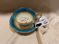 Tea cup and saucer set with turquoise and gold leaf details, floral center