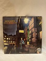 Front cover of David Bowie Ziggy Stardust vinyl record showing Bowie in alleyway with street sign 'K.West' under RCA Victor logo.