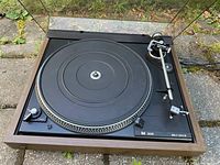 Top view of Dual 506 turntable showing black platter, tonearm assembly, and controls with wooden frame.