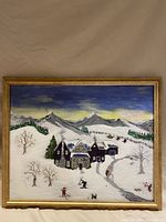 Framed folk art painting of winter snow village with mountains and people skiing and sledding.