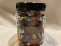 Jar filled with assorted LEGO minifigure pieces and accessories viewed from the side.