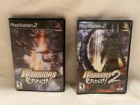 Front view of both Warriors Orochi 1 and 2 PlayStation 2 game cases side by side showing cover art and PlayStation 2 branding.