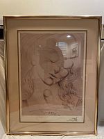 Framed Salvador Dali print showing two abstract faces with detailed line work and surrealist style.