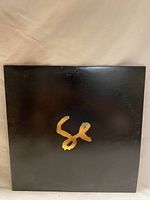 Front cover of vinyl record showing black background and gold 'SE' lettering