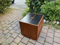Exterior view of closed teak cabinet showing black laminate top panels and recessed teak handles