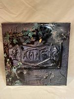 Front cover of The Damned vinyl record, showing gothic-style band name plaque entwined with ivy and stone texture.