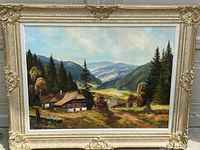 Full view of vintage landscape oil painting on canvas in ornate frame showing mountain valley scene with houses and trees.