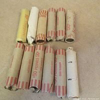 12 rolls of Canadian pennies wrapped in paper coin wrappers laid out on carpeted surface
