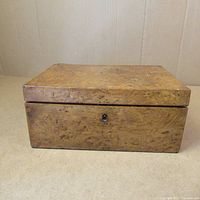 Closed view of the bird's eye maple box showing detailed wood grain and lock keyhole on front.
